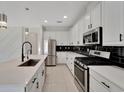 Modern kitchen with white cabinets, stainless steel appliances, and sleek black backsplash at 7408 Sungold Meadow Ct, Apollo Beach, FL 33572