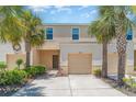 Exterior view of a townhouse with a garage, and landscaped front yard, with palm tree accents at 12841 Buffalo Run Dr, Gibsonton, FL 33534