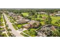 Overhead view of the home with palms, a golf course beyond, and tile roofs in the neighborhood at 13003 Carlington Ln, Riverview, FL 33579