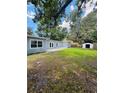 Spacious backyard featuring a lush green lawn, storage shed, and mature trees at 1507 W Le Compte Dr, Tampa, FL 33604