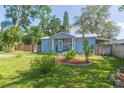 Quaint blue home featuring lush greenery and charming front yard landscaping at 1912 E 97Th Ave, Tampa, FL 33612