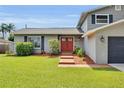 Inviting home entrance with a red front door, complemented by the home's well-kept lawn and landscaping at 3721 Casaba Loop, Valrico, FL 33596