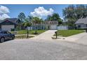View of the house on the street with a well-maintained lawn, mature trees, and blue car parked nearby at 4707 Barrett Ct, Tampa, FL 33617