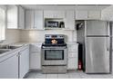 Functional kitchen features white cabinetry, stainless steel appliances, and tiled backsplash at 4775 Cove Cir # 803, St Petersburg, FL 33708