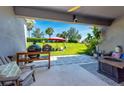 Cozy covered back patio with outdoor furniture, grill, and a view of the spacious backyard at 4906 Los Robles Ct, Palmetto, FL 34221