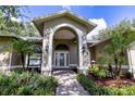 Inviting front entrance featuring an arched portico, brick accents, and lush landscaping at 8901 Eagle Watch Dr, Riverview, FL 33578