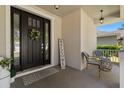 Inviting covered porch with a black front door adorned by a wreath and stylish outdoor seating at 9275 Bella Vita Cir, Land O Lakes, FL 34637