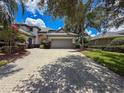 Beautiful single Gathering home with a long brick driveway, lush trees and a well-manicured lawn at 9808 Milano Dr, Trinity, FL 34655