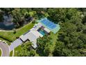 Stunning aerial view of estate featuring tennis court, pool, and a serene pond surrounded by lush greenery at 13710 Westshire Dr, Tampa, FL 33618