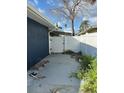 View of a fenced backyard with concrete slab with lush greenery and a gate for access at 15416 2Nd E St, Madeira Beach, FL 33708
