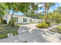 White brick home with green shutters and a long driveway framed by mature trees and a well-manicured lawn at 2320 Harn Blvd, Clearwater, FL 33764