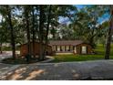 Charming single-story brick home with lush landscaping, mature trees, and a welcoming front porch at 23327 Christian Cir, Brooksville, FL 34601