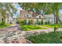This home features a lush lawn, mature tree, brick driveway, and a charming facade with dormer windows at 2512 W Jetton Ave, Tampa, FL 33629