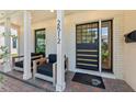 Inviting front porch with comfortable seating and a stylish modern door with a brick surround and pillars at 2512 W Jetton Ave, Tampa, FL 33629