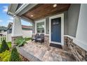 Inviting front porch features stone accents, elegant seating, and a wood ceiling, creating a cozy outdoor space at 3013 W Crest Ave, Tampa, FL 33614