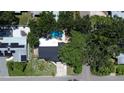Aerial view of a home with a backyard pool, mature trees, and solar panels on a neighboring roof at 5998 8Th S St, St Petersburg, FL 33705