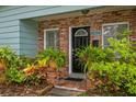 Home's front door framed by brick, adorned with lush greenery and vibrant plants at 8014 27Th N Ave, St Petersburg, FL 33710