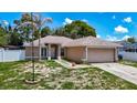 A single story home with 2-car garage, neutral paint, arched windows, and palm tree at 13337 Tubeck St, Spring Hill, FL 34609