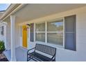 Inviting front porch features updated windows, shutters, bench seating, and bright yellow front door at 1426 Gerard Ln, Holiday, FL 34690
