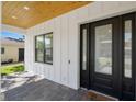 Covered front porch with a modern black front door, brick pavers, and wood ceiling at 4114 W Neptune St, Tampa, FL 33629
