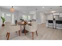 Open-concept dining area with modern lighting, wood-look floors, and a view of the kitchen at 505 Broxburn Ave, Temple Terrace, FL 33617