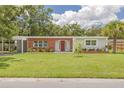 Charming single-story home with red brick accents, a spacious lawn, and mature landscaping at 505 Broxburn Ave, Temple Terrace, FL 33617