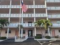 Exterior shot of a multi-story residential building with balconies and a flagpole displaying the American flag at 6025 Shore S Blvd # 408, Gulfport, FL 33707
