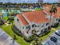 Beautiful exterior showcasing the terracotta roof, lush landscaping, assigned parking, and the nearby lake at 6080 Bahia Del Mar Cir # 109, St Petersburg, FL 33715