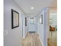Bright hallway with wood-look flooring, decorative artwork, and a view into the adjacent living spaces at 8211 Brent St # 815, Port Richey, FL 34668