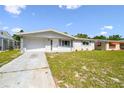 Charming single-story home featuring a well-maintained lawn, garden bed, and attached garage under a blue sky at 10831 Manchester Rd, Port Richey, FL 34668