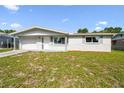 Charming single-story home featuring a well-maintained lawn and attached garage under a blue sky at 10831 Manchester Rd, Port Richey, FL 34668