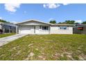 Charming single-story home featuring a well-maintained lawn and attached garage under a blue sky at 10831 Manchester Rd, Port Richey, FL 34668
