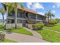 Condominium exterior with green grass, landscaping, and staircase to unit at 2420 Winding Creek Blvd # 209, Clearwater, FL 33761