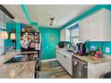 Efficient kitchen featuring granite countertops, stainless steel appliances, white cabinetry, and vibrant teal walls at 3427 Cantrell St, Holiday, FL 34690