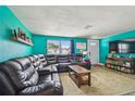 Spacious living room with a comfortable leather sectional, bright teal walls, and natural light from a large window at 3427 Cantrell St, Holiday, FL 34690