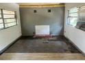 Empty living room with two windows, damaged flooring, and a non-functioning fireplace at 3518 16Th S Ave, St Petersburg, FL 33711