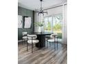 Modern dining room boasts a round table, chic chairs, modern chandelier, and natural light from the glass patio door at 36972 Sagemoor Dr, Zephyrhills, FL 33541