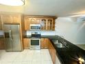 Well lit kitchen with stainless steel appliances, dark countertops, wooden cabinets and tile floor at 6344 Newtown Cir # B2, Tampa, FL 33615