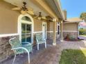 Comfortable covered front porch featuring ceiling fans, stone accents, and a brick paved area at 11362 Heritage Way, Largo, FL 33778