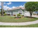 Side view of a home with light green exterior and a manicured lawn with a sprinkler system at 11439 Golf Round Dr, New Port Richey, FL 34654