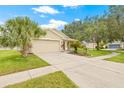 A one-story home with a well-manicured lawn, sidewalk, and a spacious driveway leading to an attached garage at 11830 Autumn Creek Dr, Riverview, FL 33569