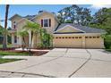 Charming two-story home with a three car garage, palm trees, and manicured lawn at 16102 Colchester Palms Dr, Tampa, FL 33647