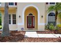 Charming front door with an arched entryway, decorative sidelights, and lush landscaping at 16102 Colchester Palms Dr, Tampa, FL 33647