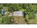 An aerial view showcases the home, the yard, shed, and surrounding verdant landscaping and neighborhood at 2121 Odessa Gardens Ln, Odessa, FL 33556