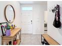 Inviting foyer featuring tile flooring, console table with mirror, and coat rack upon entry at 34033 Jasper Stone Dr, Wesley Chapel, FL 33543