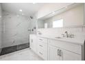This bathroom features a glass shower, marble floors, and a double sink with white cabinets and a large mirror at 4015 Overlook Ne Dr, St Petersburg, FL 33703