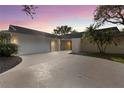 Home exterior showcasing a two-car garage, manicured lawn, driveway, and exterior lighting at 4157 Marine Pkwy, New Port Richey, FL 34652