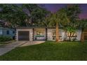 Dusk view of a modern one story home with black trim, a front lawn and mature landscaping at 4441 16Th N St, St Petersburg, FL 33703