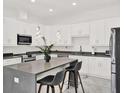 Bright kitchen featuring white cabinets, marble floors, gray counters, and a spacious center island with bar seating at 5006 W Idaho St, Tampa, FL 33616