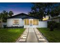 Charming single-story home boasts a screened-in porch, manicured lawn, and inviting walkway at dusk at 5055 9Th St, Zephyrhills, FL 33542